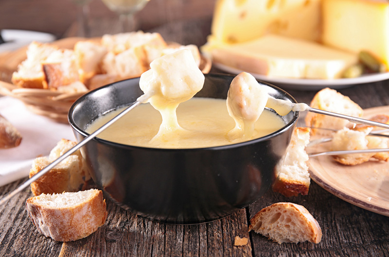 Brødbiter på spidd dyppes i smeltet ost: Fondue.