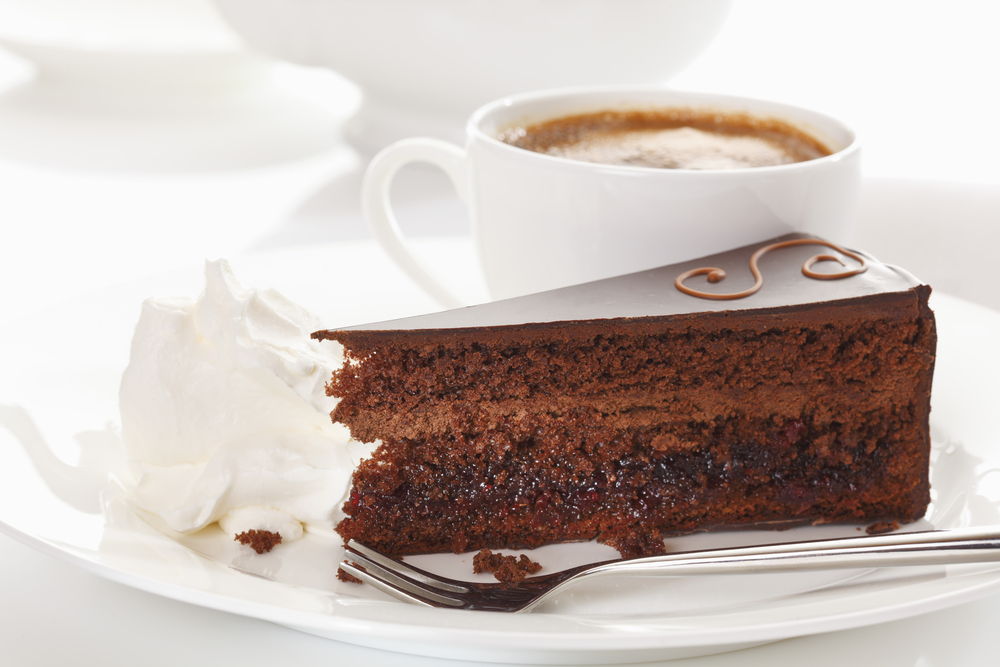 Brun kake med hvite lag på et utendørs cafébord: Sachertorte.